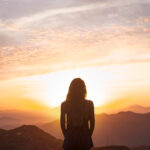 vista-posterior-mujer-haciendo-yoga-mientras-ve-puesta-sol